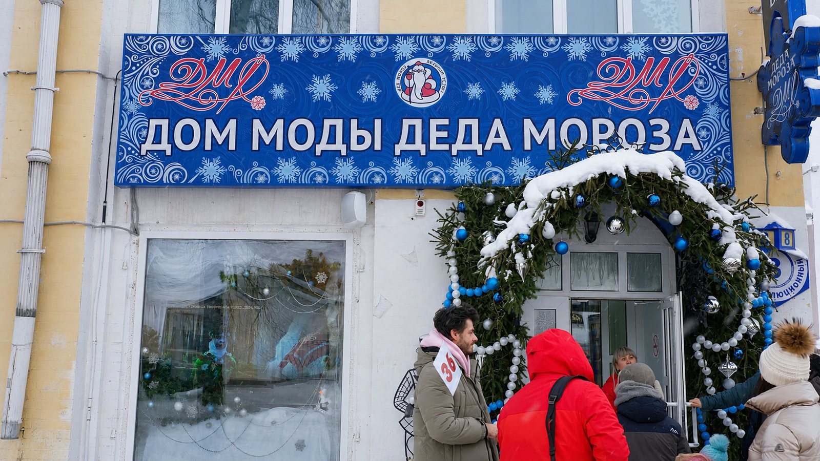 Фасад с большой синей вывеской «Дом моды Деда Мороза» и посетителями у входа.