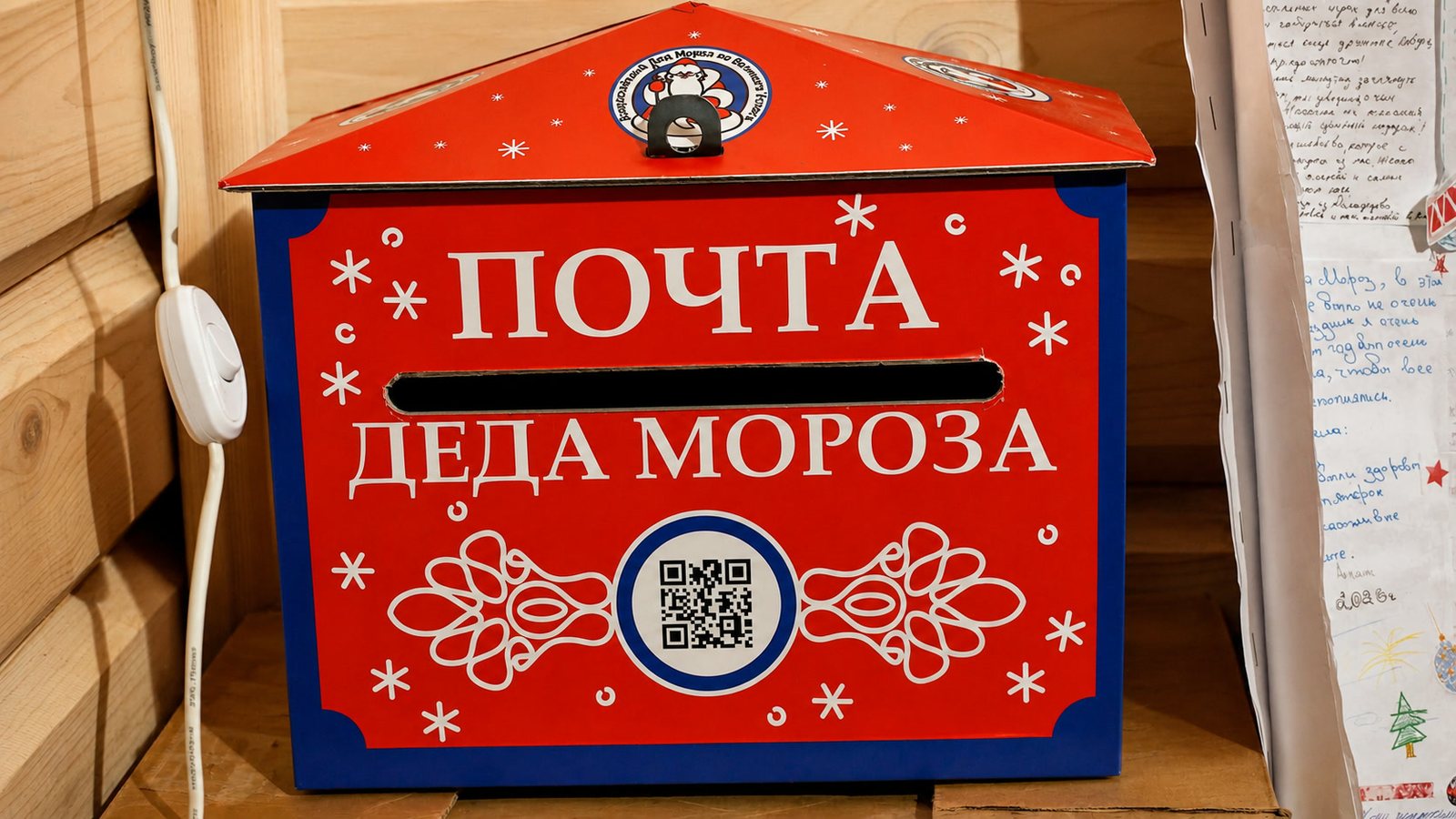 Красный настенный почтовый ящик с крупной надписью «Почта Деда Мороза» и QR-кодом.